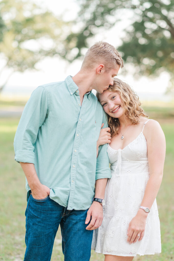 Groom kisses his fiancée on the forehead during a romantic engagement session at Turkey Creek Park in the Florida Panhandle.