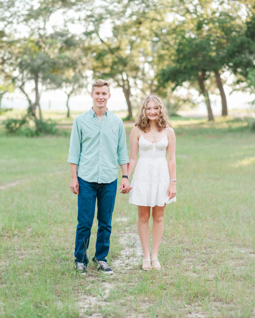 Aubrey and Nolan smiling while holding hands during their engagement session at Turkey Creek Park near Florida's Emerald Coast.