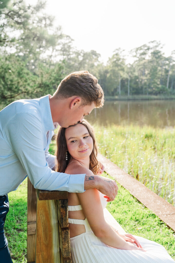 Groom-to-be kissing his fiancée beside the waterfront at Eden Gardens State Park in Santa Rosa Beach, Florida.